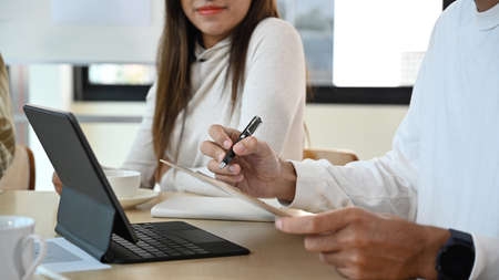 Cropped shot creative people meeting, discussing online information together at office desk.