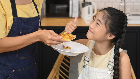Asian child cooking with mother in kitchen, spending leisure time together at home.の写真素材