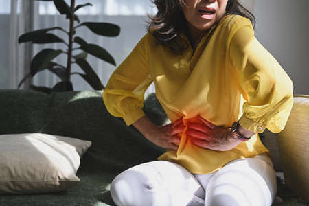 Unhappy middle aged lady touching belly, suffering from abdomen ache, symptoms gastrointestinal system disease, gut, digestion problems.の写真素材