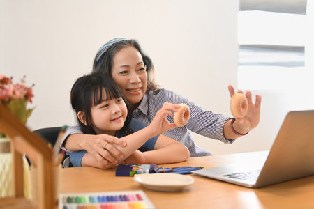 Loving mature grandma and little grandchild having video call on laptop computer at home together. Multi generational, family and love concept.の写真素材