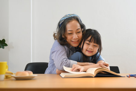 Caring grandma telling story, reading fairy tale to her little granddaughter. Multi generational, family and love concept.の写真素材