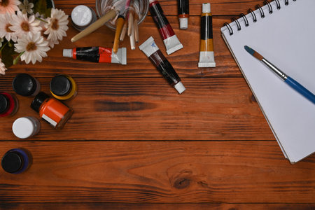 Blank notepad, paint brushes and watercolors on wooden background. Artistic background, top view, flat lay.の写真素材