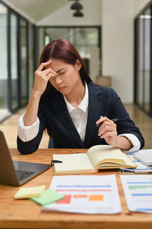 Overworked young businesswoman suffering from headache, stress at work or upset after finishing meeting .の写真素材