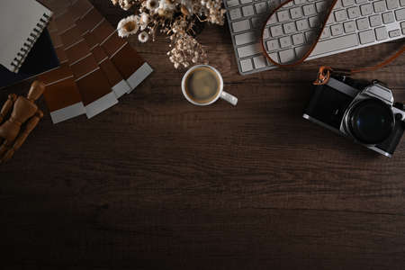 Top view creative workspace with camera, color swatches, notebook and coffee cup on wooden...