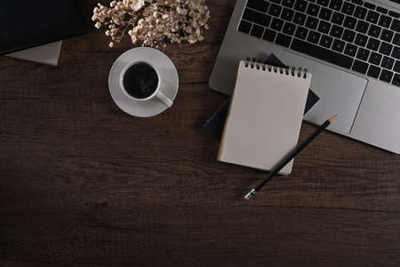 Blank notepad, laptop computer, coffee cup and flower pot on wooden desk. Flat lay, Top view.の写真素材