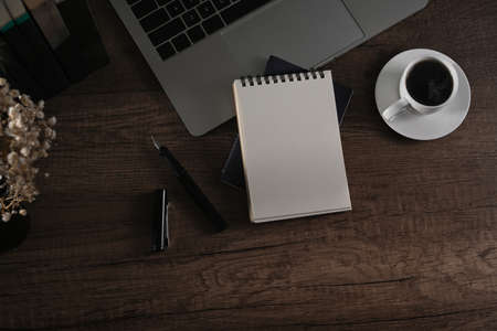 Empty notepad, laptop computer, coffee cup and flower pot on wooden desk. Flat lay, Top view.