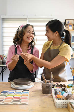Happy mile aged lady making ceramic pot in pottery workshop. Activity, handicraft, hobbies concept.