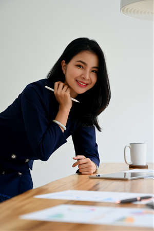 Successful finance manager planning work projects and using digital tablet at her modern workplace.の写真素材