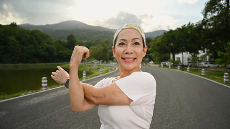 Smiling mature woman stretching her muscle after workout session in the evening.の写真素材
