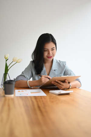 Pretty young woman entrepreneur reading financial reports at office desk.