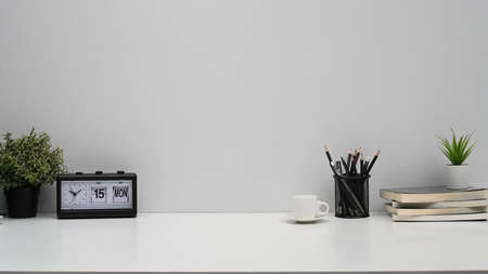 Home office desk with alarm clock, books, coffee cup and pencil holder. Copy pace for your advertise text.の写真素材