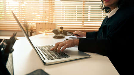 Cropped image of professional female lawyer working with documents and laptop in bright office.の写真素材