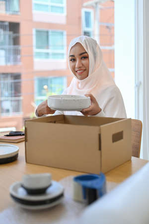 Beautiful Muslim woman in hijab preparing parcel boxes of product for shipping to customers.の写真素材