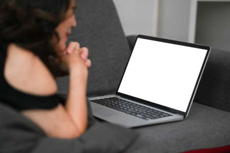 Relaxed mature woman lying on couch and watching movie in laptop computer.の写真素材