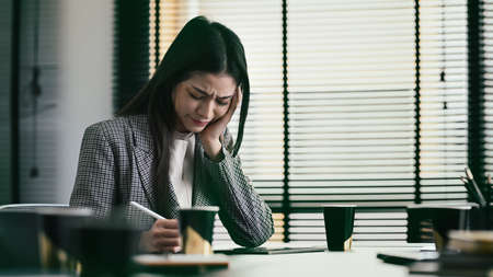Frustrated businesswoman tired and stressed about work. Stressful life and deadlines concept.の写真素材