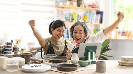 Exited craft pottery shop owners celebrating after finish big order from customer. E-commerce,...