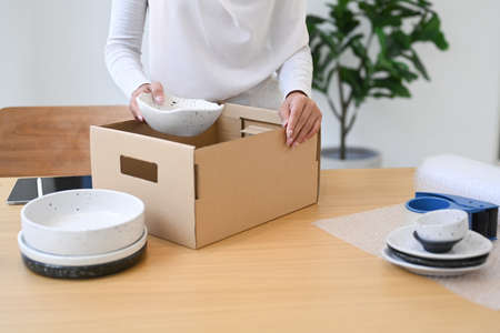 Young Muslim woman small business owner packing product in cardboard box for shipping to customers.