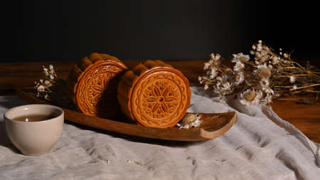 Traditional mooncakes on wooden table setting with teacup. Mid Autumn festival or Chinese...