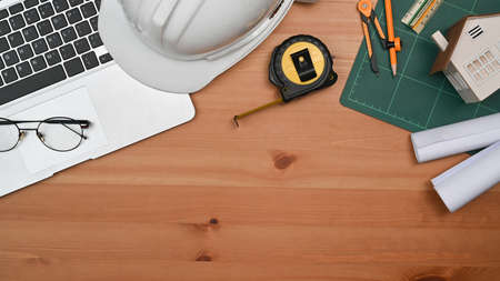 Laptop computer, glasses, protective helmet and blueprints on a wooden table. Engineer, Architect office desk.の写真素材