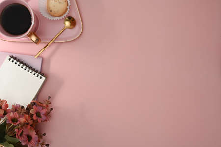 Notepad, coffee cup and red flower on pink background. Top view, flat lay, copy space for text.の写真素材