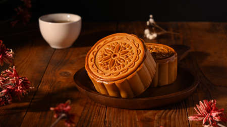 Delicious traditional Chinese moon cakes and tea on wooden background. Mid autumn festival or...