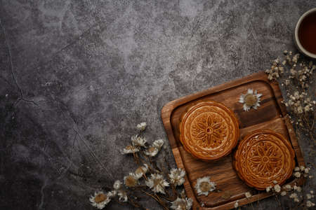 Traditional Chinese mooncakes decorating with dried flower on grey rustic background. Top view with copy space.の写真素材