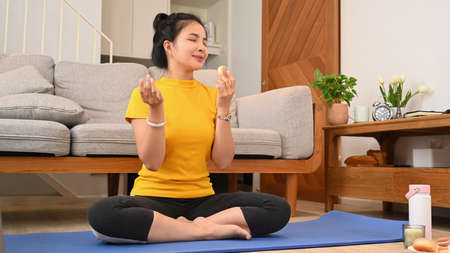 Healthy woman practicing yoga on mat, trying to resist temptation.