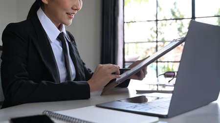 Smiling asian woman using laptop and planning work projects at her modern workplace.