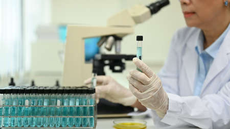Professional mature female scientist examining samples and liquid in laboratory. Medicine and science researching concepts.の写真素材