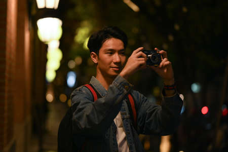 Man using smart phone while sitting on stairs in the night city with blurred night street lights background.の写真素材