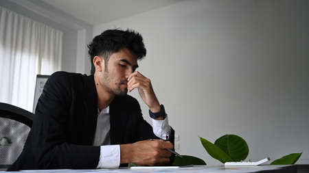 Focused male entrepreneur analyzing financial data at his office desk.の写真素材