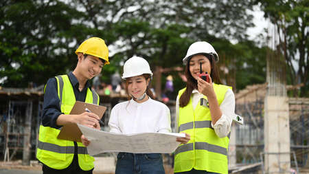 Female investor and engineers discussing, planning development details together at construction site.の写真素材