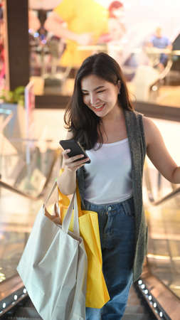 Caucasian woman carrying bags with shopping in shopping mall.の写真素材