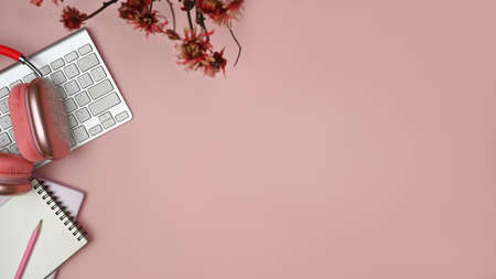 Top view copy space with office desk with keyboard, head phone, pencil and notepad on pink table with above shot.の写真素材