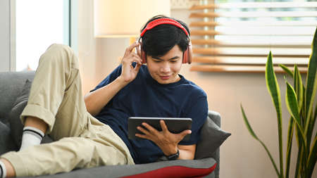 Casual man wearing wireless headphone and watching movie on his digital tablet.の写真素材