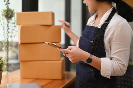 Small business entrepreneur wearing apron working at her home office. Online selling, e-commerce...