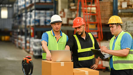 Warehouse workers and manager in safety helmet working in storage factory. Distribution center and...