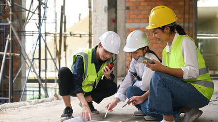 Civil engineer team and supervisor sitting in construction site floor and discussing on plan while...