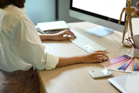 Cropped shot of graphic designers working with color swatches and computer at contemporary workplace.の写真素材