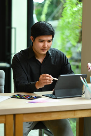 Portrait of asian male interior designer working online with digital tablet at modern home office.の写真素材