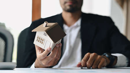 Cropped imaged of male investor with house model in his hand. Real estate, mortgage loan and home...