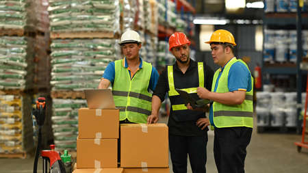 Warehouse managers and workers discussing, checking supply export shipment while standing in retail...