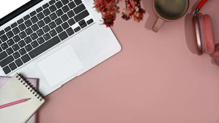 Feminine workspace with laptop, blank notepad, wireless headphone and coffee cup. Top view with copy space.の写真素材