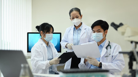 Team of young research scientists and senior supervisor discussing about new test results, working...