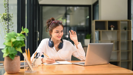 Pretty young female student chatting online, listening lecture during study online on laptop....