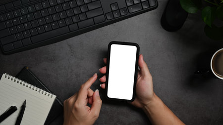 From above view man using mobile phone on black stone table. Blank screen for your text.