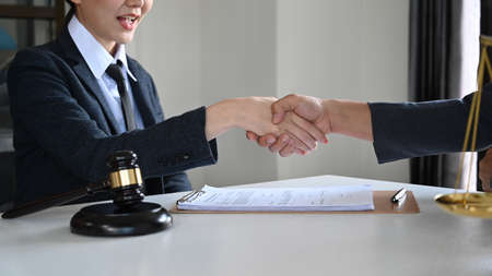 Friendly female lawyers or attorney shaking hands with clients after a contract agreement.