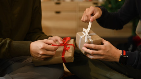 Cropped image of men celebrating Christmas, New Year at home together and exchange presents. Holidays and celebration concept.の写真素材