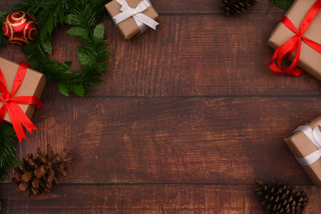 Top view of Christmas gift boxes, fir tree branches and pine cones on wooden background. Christmas background concept.の写真素材