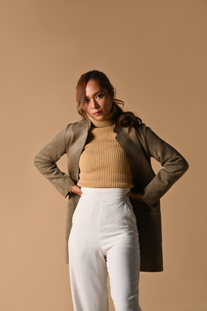 Portrait of fashionable woman in trench coat standing on beige background. Autumn fashion and beauty concept.の写真素材